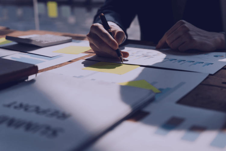 Table with papers on it and a man working.