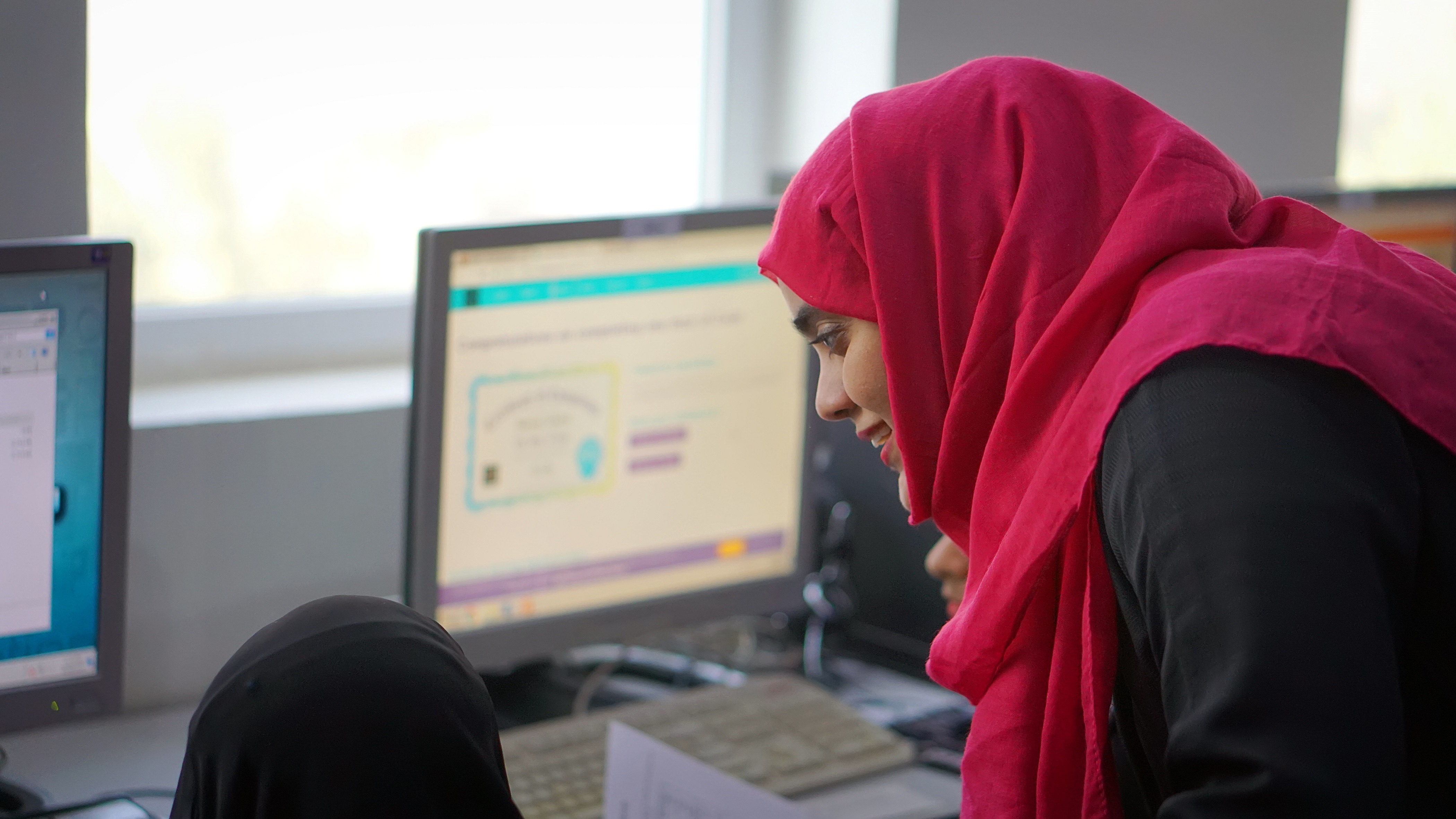 Tawtheef Program AMIDEAST Yemen Training Coordinator is helping a female Tawtheef recipient while doing an assignment on her computer.
